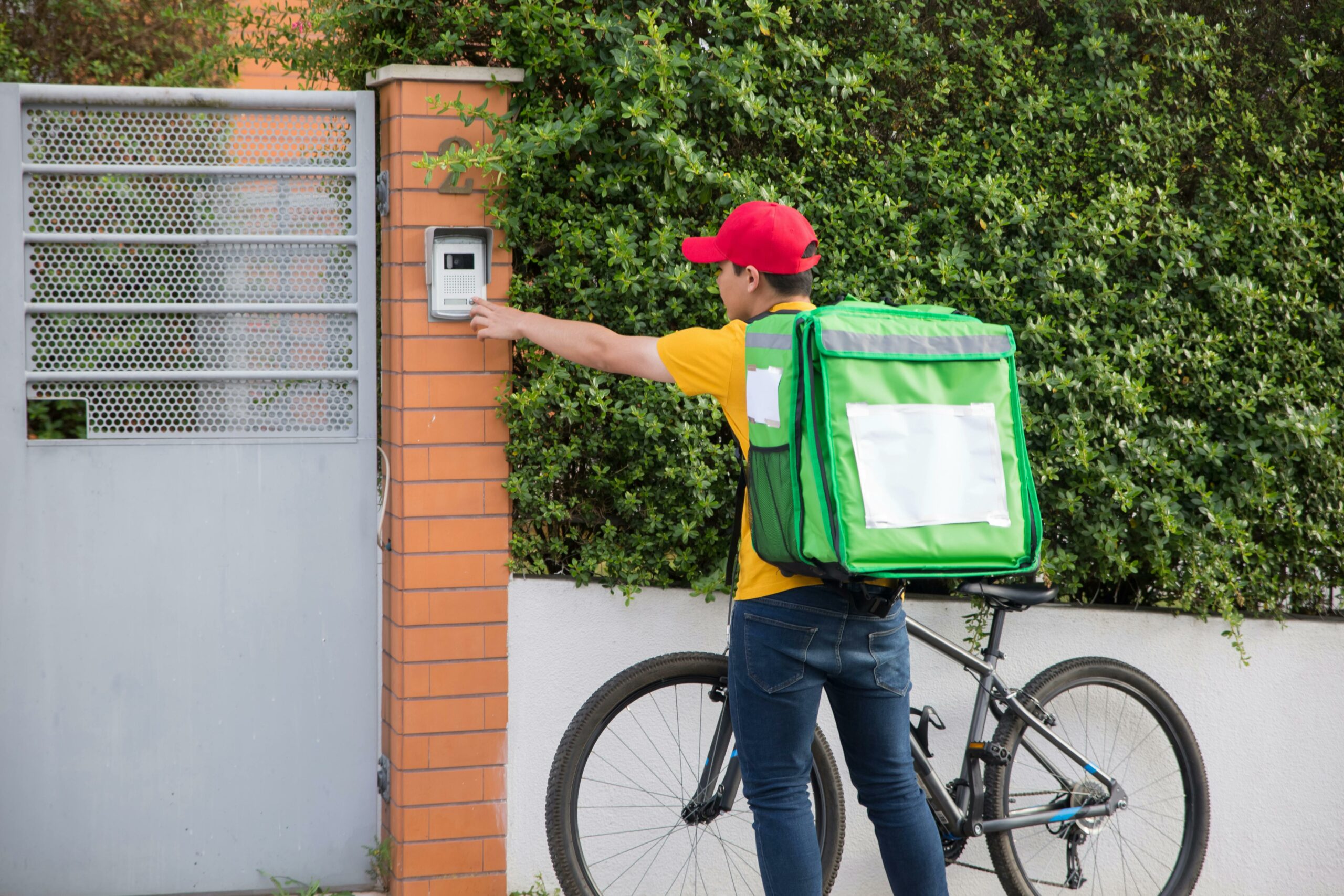 Livreur à vélo sonnant à l'interphone d'une maison