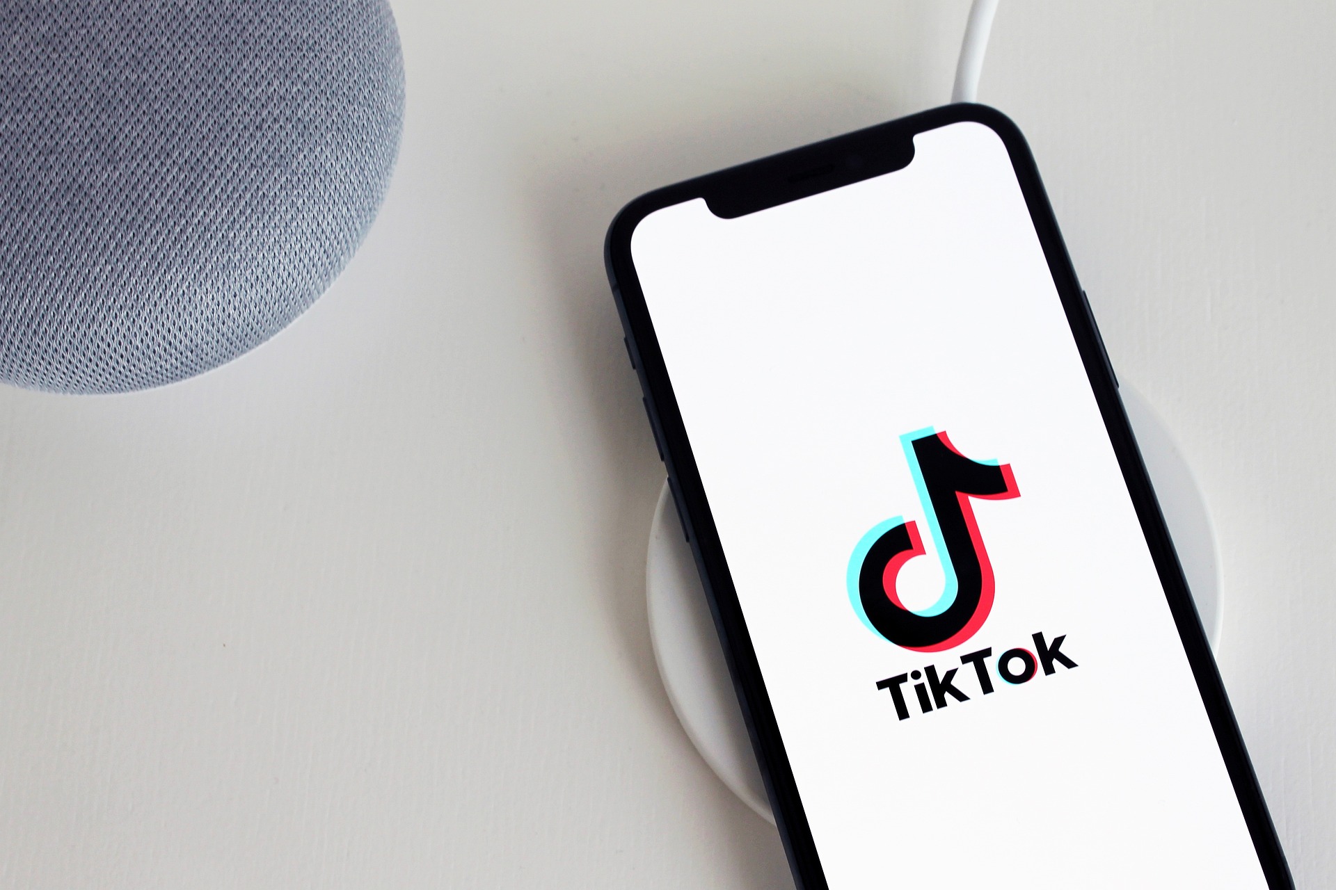 Smartphone affichant le logo TikTok posé sur un chargeur.